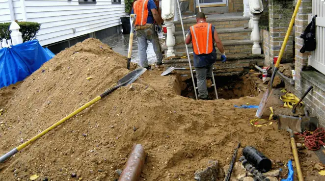 Contractors performing foundation protection and exterior drainage excavation near residential home steps in Cleveland, OH