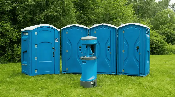 Four blue portable toilets and a matching hand washing station on grass near trees, a common sight at local outdoor events in Cleveland, OH